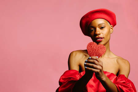 attractive young woman in red, smiling and holding a red heart, be my valentineの写真素材