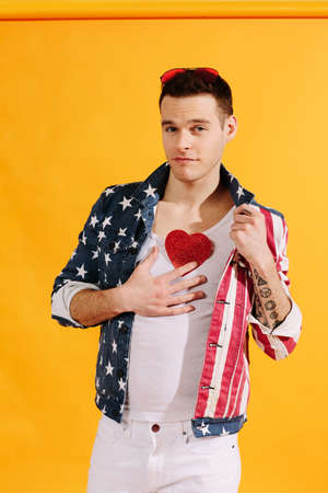 cute guy in american flag jacket holding red heart on his chestの写真素材