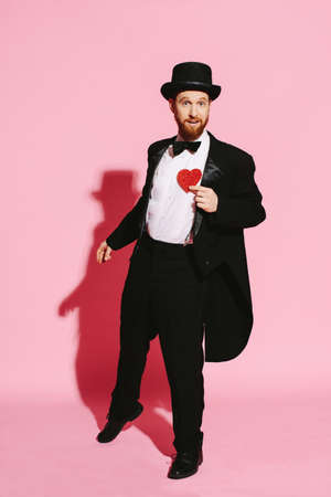 dancing man in a tuxedo and top hat holding a red heartの写真素材