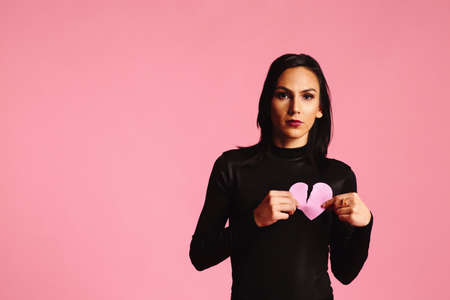 Woman holding a ripped, broken pink heartの写真素材