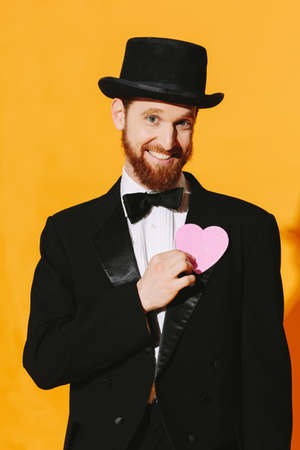 Hopeful smiling man with top hat holding a pink heart, be my valentineの写真素材