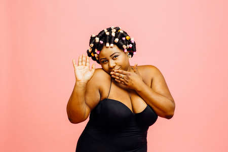 Woman with hair curlers and neglige kissing hand and waving, isolated on pink backgroundの写真素材