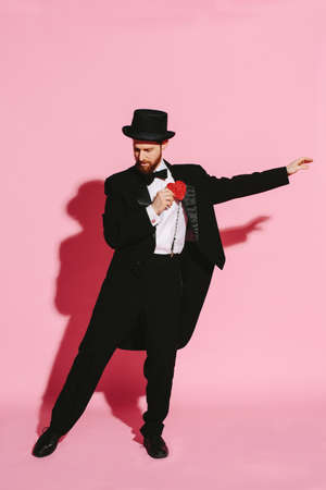 dancing man in a tuxedo and top hat holding a red heart