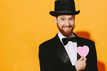 Hopeful smiling man with top hat holding a pink heart, be my valentineの写真素材