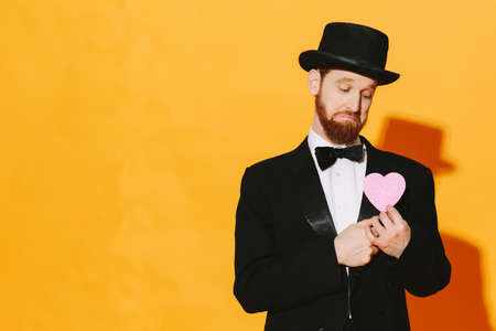 Sad man with top hat holding a pink heart, be my valentineの写真素材