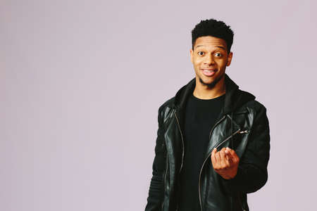 Cool young man pointing at camera with his index finger in a studioの写真素材