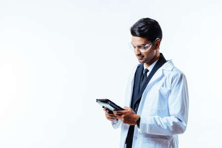 Portrait of a man in business suit, lab coat and protective glasses, holding leather folder, isolated on white studio backgroundの写真素材