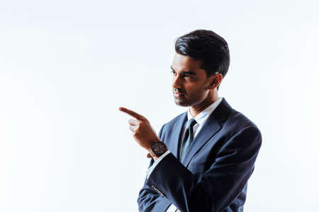 Portrait of a handsome man in suit pointing and looking to the side, isolated on white studio backgroundの写真素材