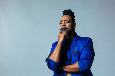 portrait of a man with blue lips dressing in blue sitting . Studio photo shoot. Pride. Surprised....