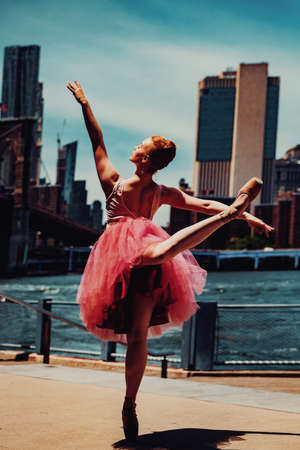 elegant ballerina in dress dancing with cityscape on backgroundの写真素材