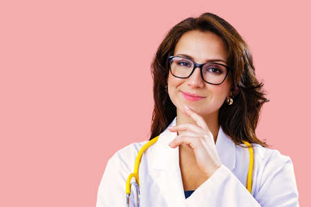 Close up studio portrait of a smiling young female doctor or nurse in glasses with stethoscope looking aheadの写真素材