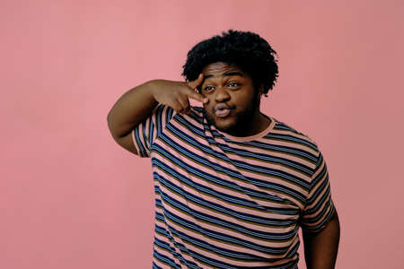 young happy african american man posing in the studio over pink backgroundの写真素材