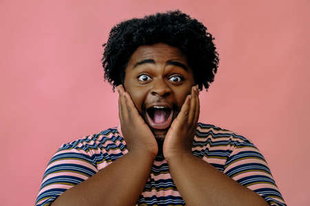 young happy african american man posing in the studio over pink background