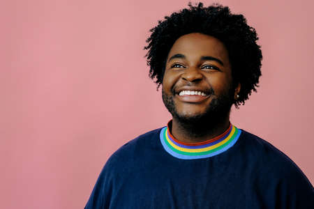 young happy african american man posing in the studio over pink background male modelの写真素材
