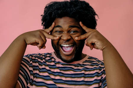 young happy african american man posing in the studio over pink backgroundの写真素材