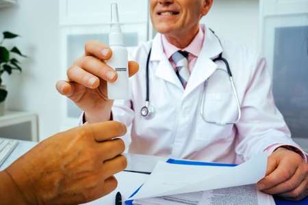 smiling doctor physician and nurse practitioner giving nasal spray to female patient in hospital...