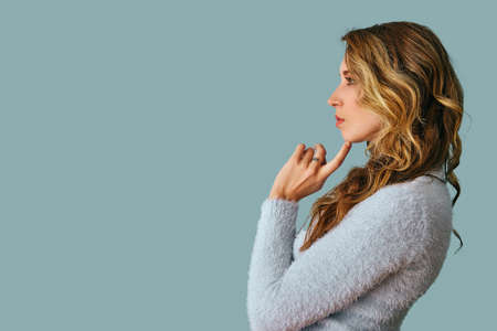 portrait of beautiful young pensive thoughtful woman with long curly hair looking away at copy spaceの写真素材