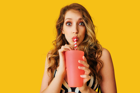 young adult woman holding fruit juice cocktail on color background summertimeの写真素材