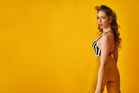 beautiful young woman in a swimsuit top on a yellow backgroundの写真素材