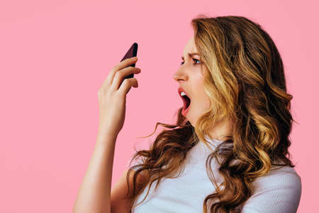 beautiful happy woman taking selfie shocked with smartphone pink backgroundの写真素材