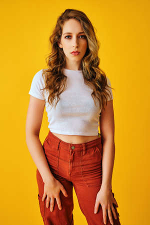 portrait of attractive young woman posing against yellow background