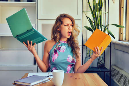 young adult stressed entrepreneur woman with books and laptop in the library bankruptcyの写真素材