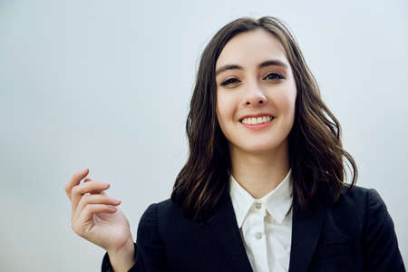 close up portrait of a beautiful smiling young businesswoman wearing black jacket on a white background looking at cameraの写真素材