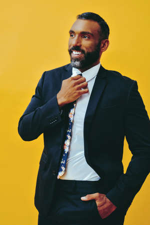 portrait of handsome bearded man in suit and tie, isolated on yellow background hand in pocket and tie profileの写真素材