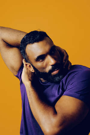 closeup portrait of a handsome sensitive young adult man dancing with purple t-shirt on a yellow...