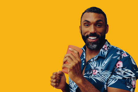 happy smiling african american man wearing Hawaiian shirt with cocktail glassの写真素材