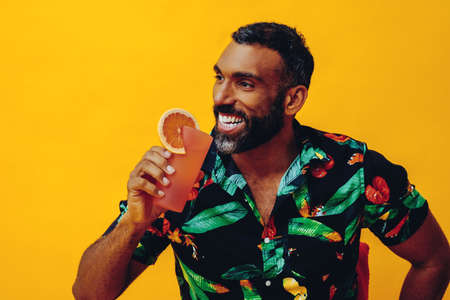 handsome bearded mid adult african american man smiling on vacation sitting on a chair drinking...