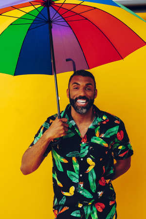 handsome smiling bearded african american man in Hawaiian shirt posing with colorful rainbow...