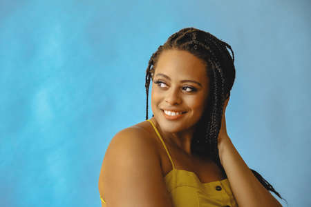 closeup portrait of smiling young beautiful african american woman braid hair posing at studio looking away at copy spaceの写真素材