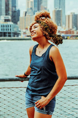 Portrait beautiful young adult woman afro hairstyle with Manhattan New York City skyline in the background outdoorsの写真素材