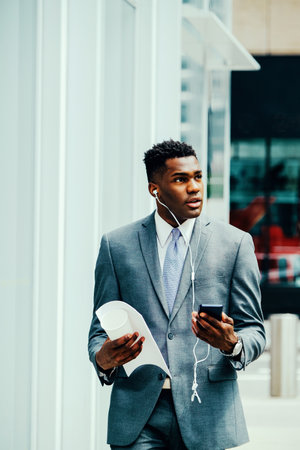 Young businessman using smartphone outside wearing suitの写真素材