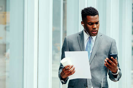 Young entrepreneur using smartphone outside wearing suitの写真素材