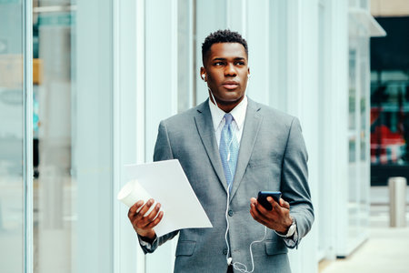 Young businessman using smartphone outside wearing suitの写真素材