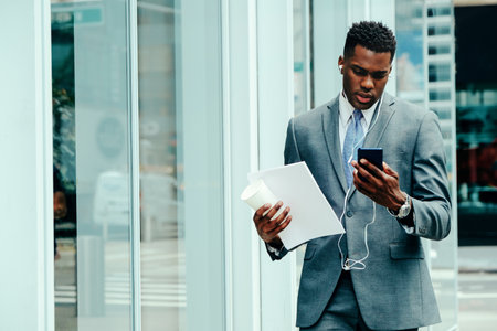 Young businessman using smartphone outside wearing suitの写真素材