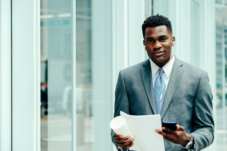 Positive young businessman using smartphone outside wearing suitの写真素材