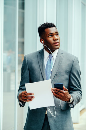 Young businessman using smartphone outside wearing suitの写真素材