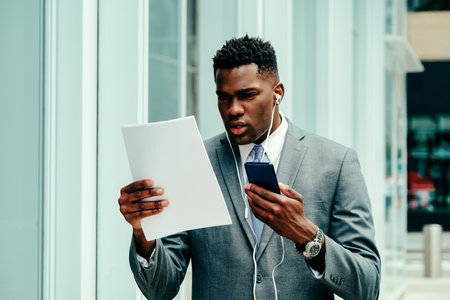 Young businessman using smartphone outside wearing suitの写真素材