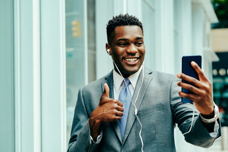 Positive young businessman using smartphone outside wearing suitの写真素材