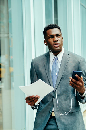 Young businessman using smartphone outside wearing suitの写真素材