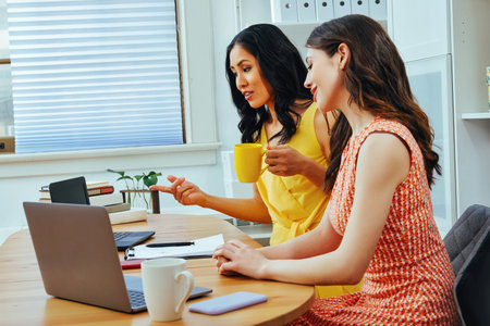 Entrepreneur woman talking looking at laptop screen and smiling while sitting at modern officeの写真素材