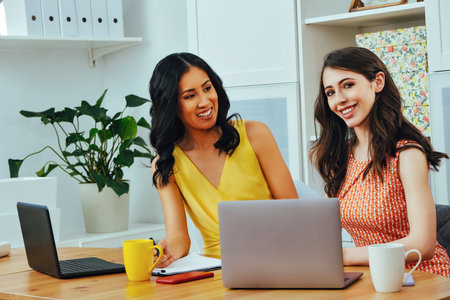Businesswoman looking at camera and smiling while sitting at modern officeの写真素材
