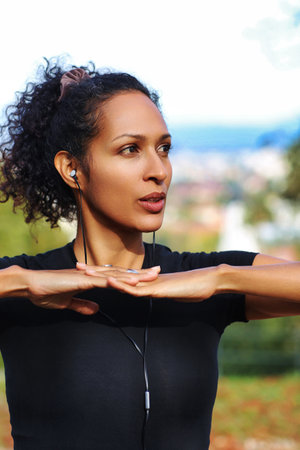 close up woman outdoors with earphones and curly hairの写真素材