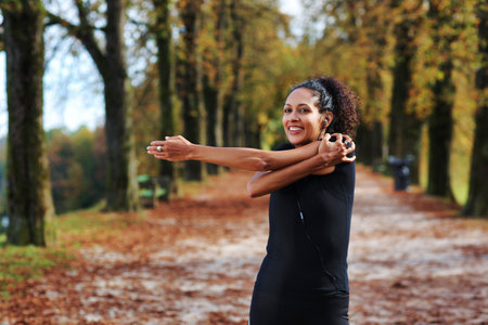 positive middle aged woman stretching outdoors preparing for exerciseの写真素材