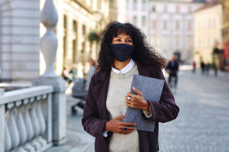 businesswoman standing in street with face maskの写真素材