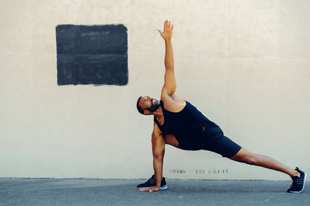 A fit athlete wearing sports clothing is exercising indoors to increase their strength, balance and flexibility for improved wellbeing and vitality.の写真素材