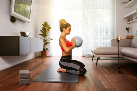 fitness online instructor teaching virtual class with exercise ball at homeの写真素材